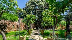 A stone pathway leading through a garden with a pergola overhead and a stone wall in the background. - Badia del Casale (Ugento)