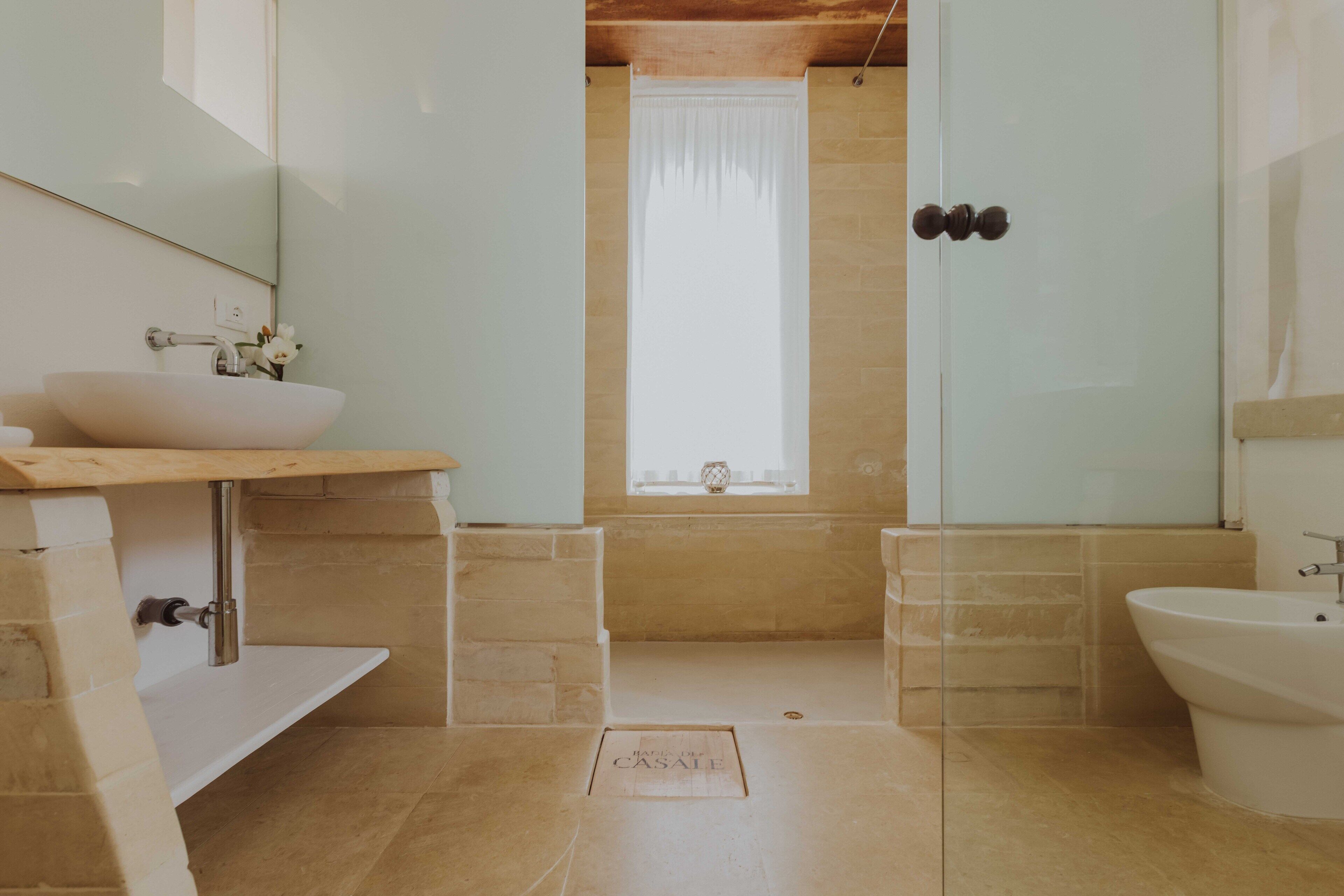 Une salle de bain avec un grand lavabo blanc, une douche en verre et une baignoire séparée.