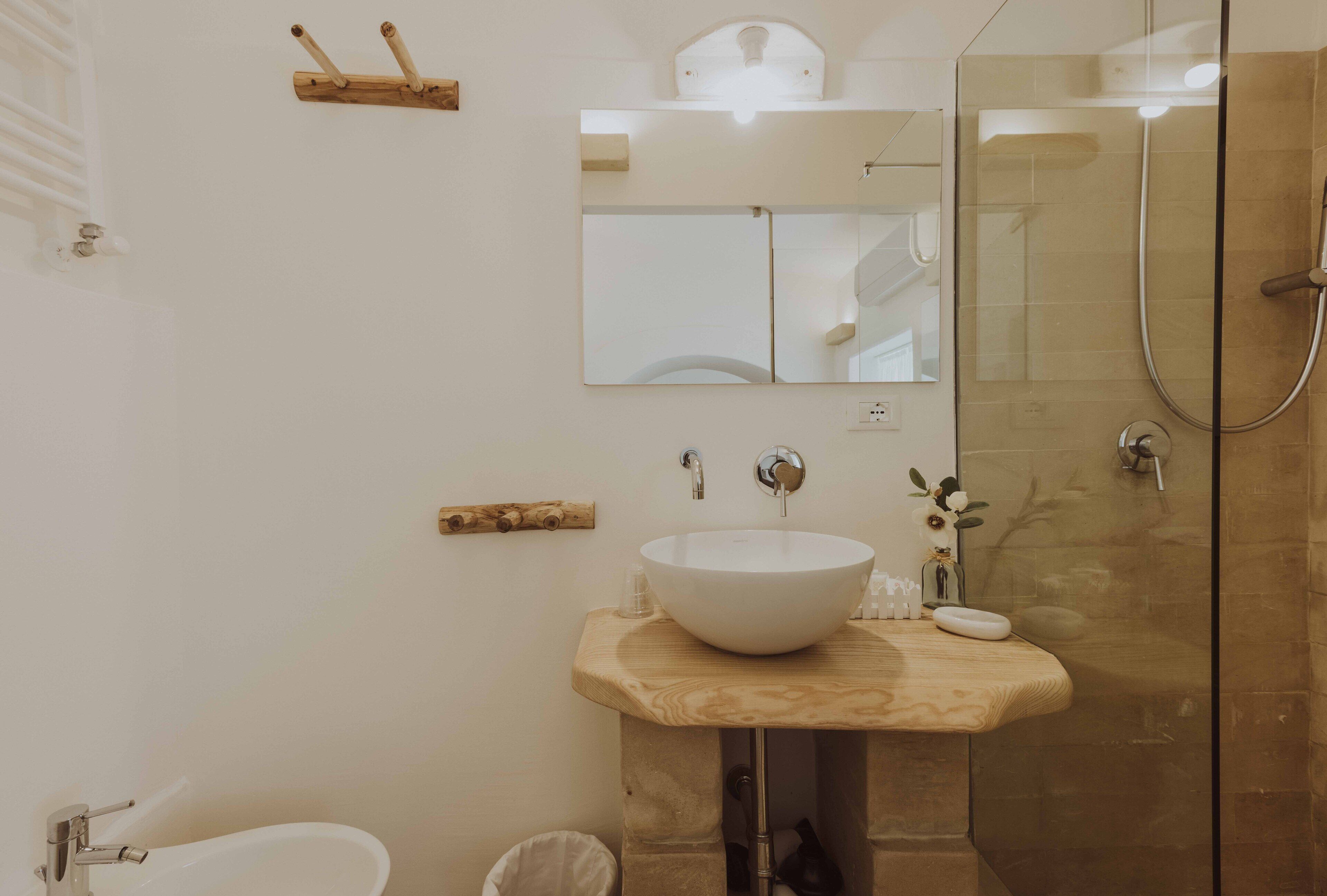 A modern bathroom with a large white sink, a mirror, and a glass-enclosed shower.