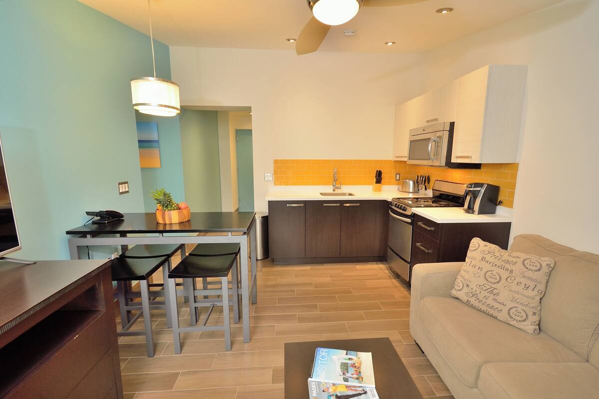 A compact living space with a dining area, kitchenette, and a sofa with a patterned pillow.