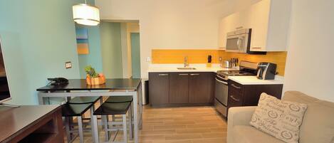 A compact living space with a dining area, kitchenette, and a sofa with a patterned pillow.