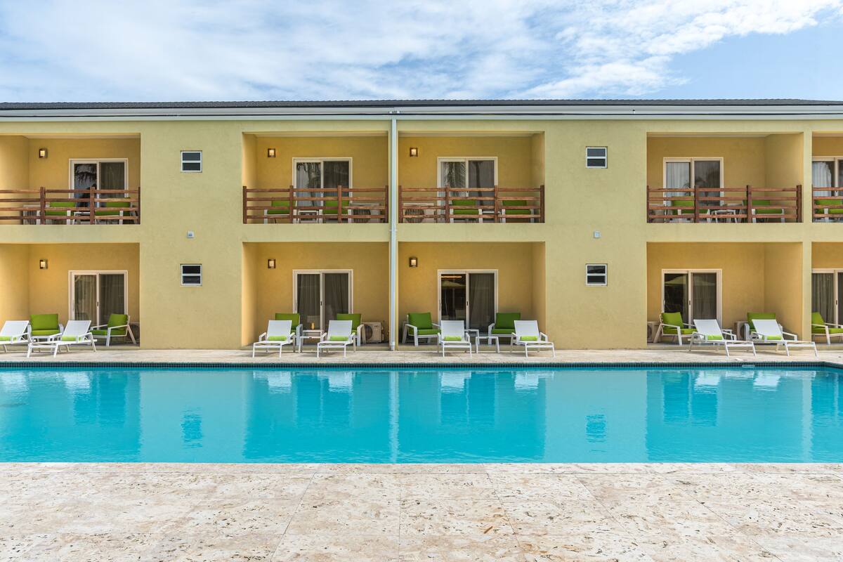 A hotel with a pool, multiple balconies, and outdoor seating areas.