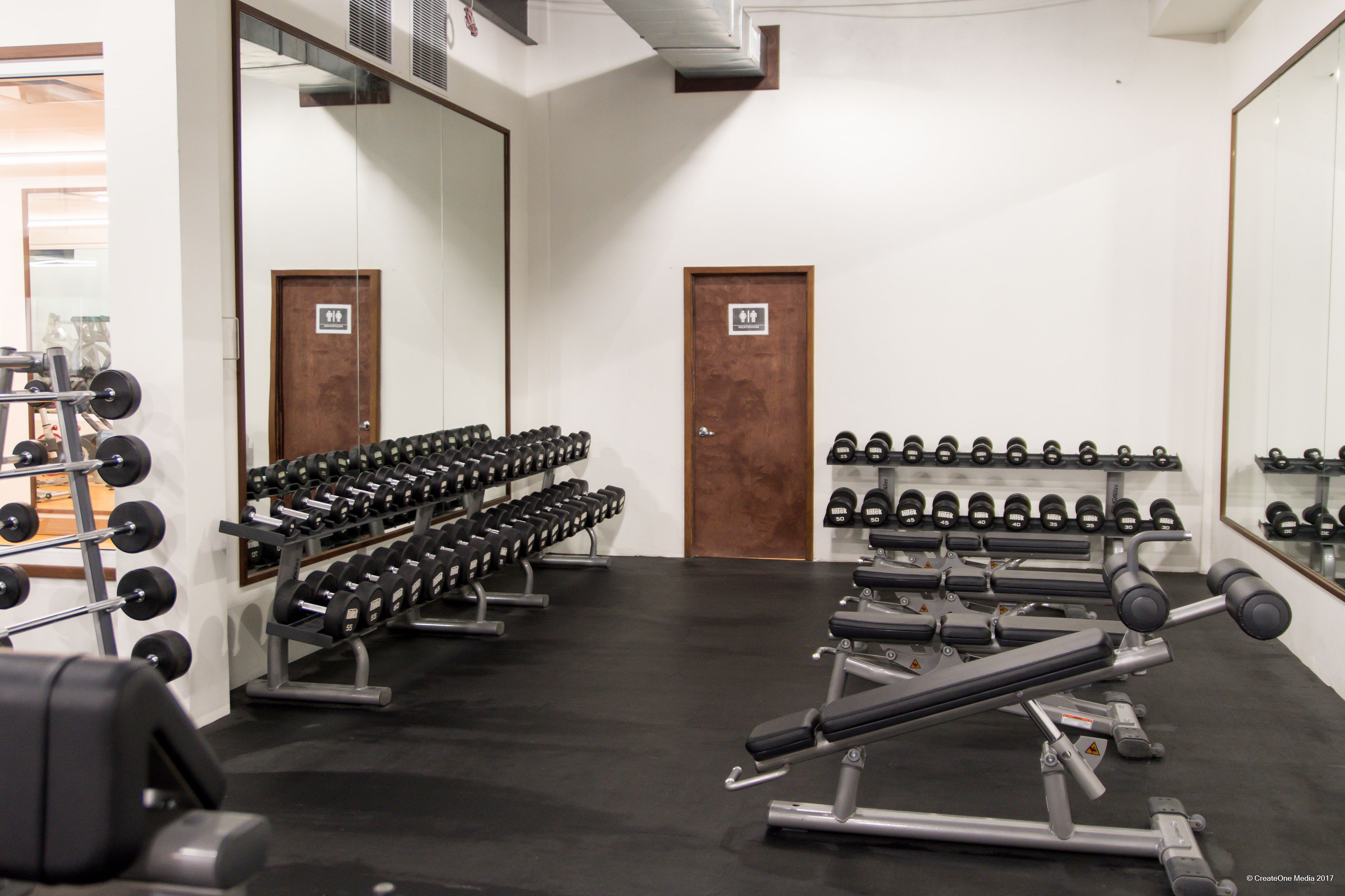 A gym with weightlifting equipment and dumbbells.
