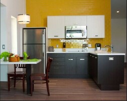 Una cocina moderna con salpicadero amarillo, electrodomésticos de acero inoxidable y armarios oscuros.