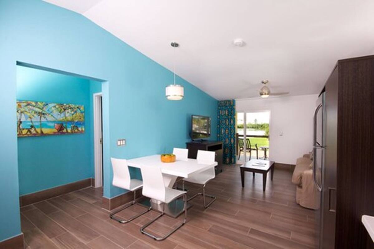 A modern kitchen with a dining area, featuring a white table, chairs, and a blue accent wall.