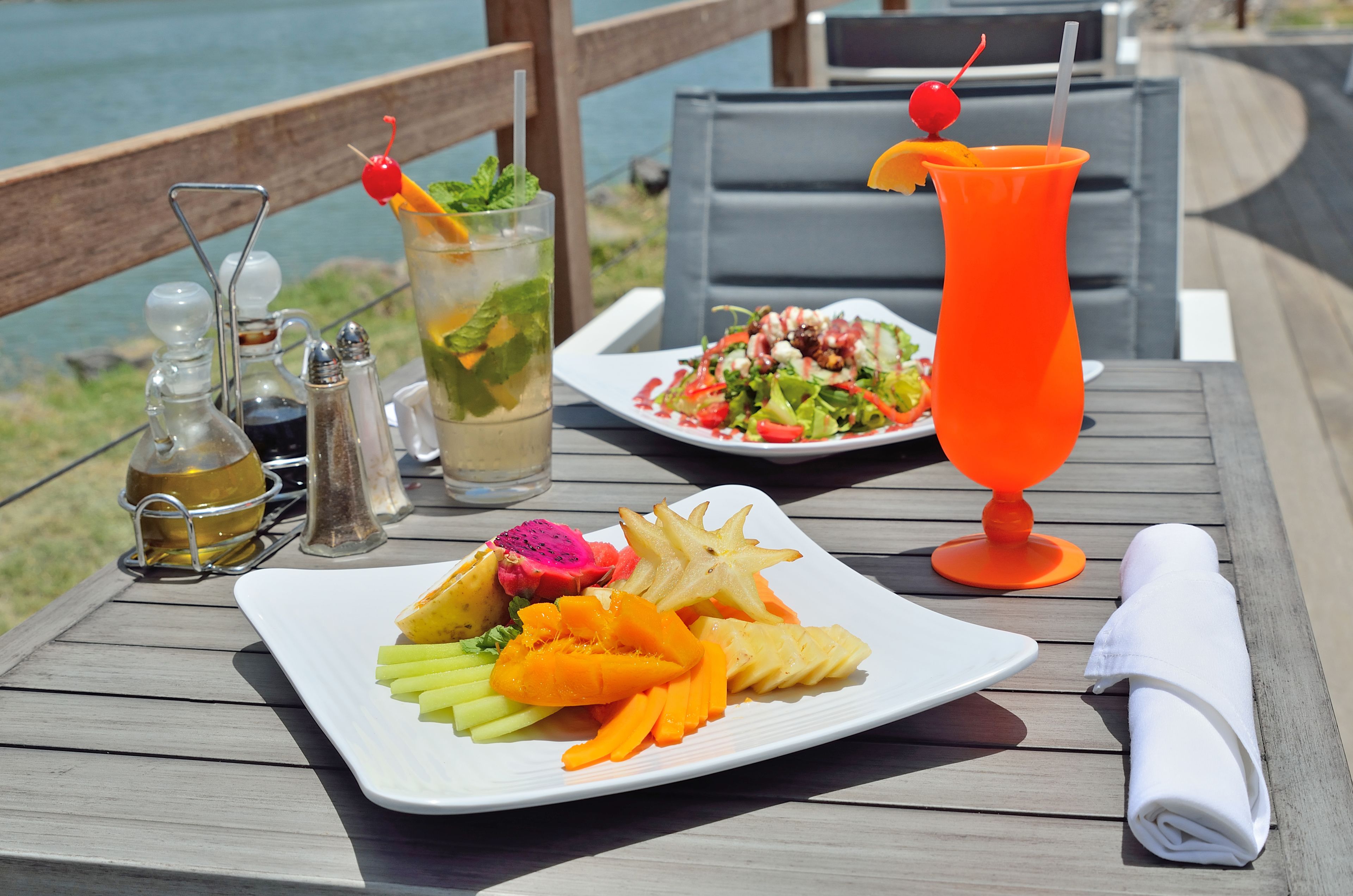 Ein Tisch mit einer Fruchtschale, einem Cocktail und Beilagen.