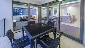Un interior moderno con un separador de vidrio que divide un área de comedor con una mesa y sillas negras del área de la cocina.