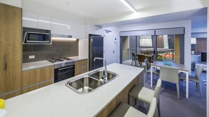 Una cocina moderna con electrodomésticos de acero inoxidable, una isla central con un lavamanos y una zona de comedor con mesa y sillas.