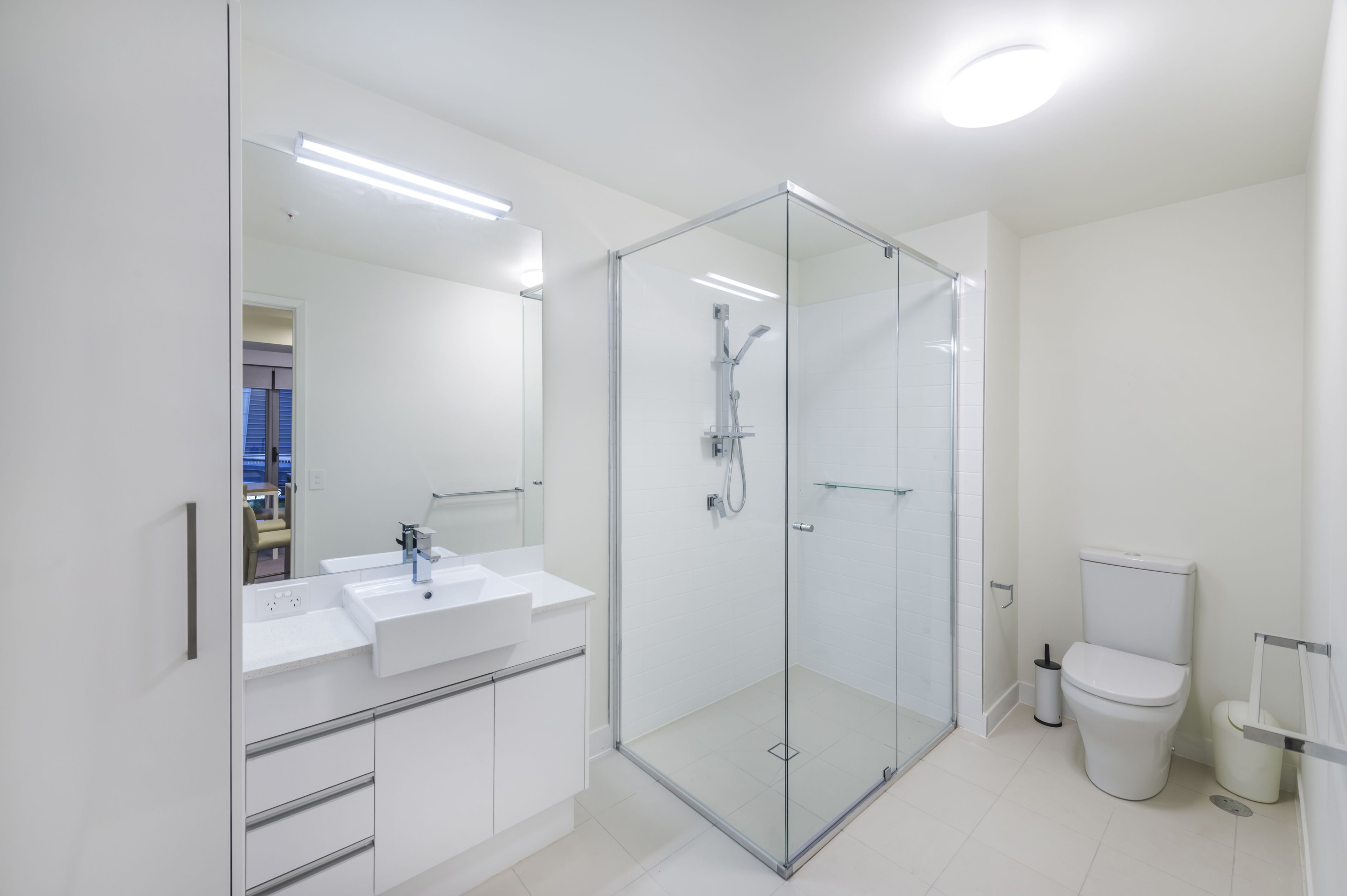 Un baño moderno con ducha envuelta en vidrio, un lavabo blanco y un inodoro.