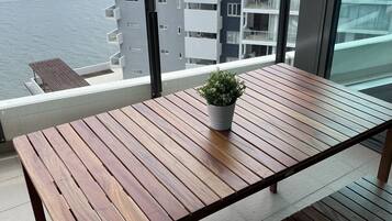 Een houten tafel met een bloempot op een balkon met uitzicht over de stad.