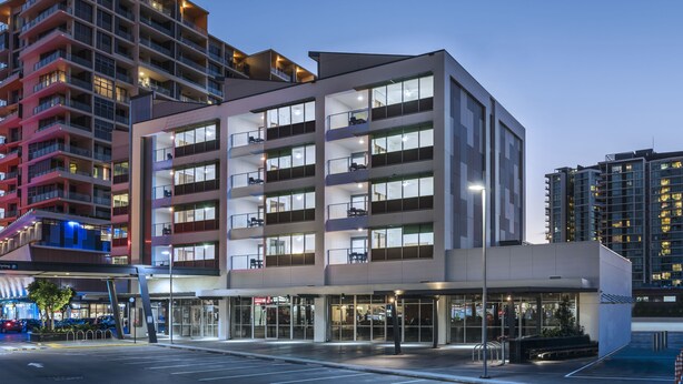 Un hotel moderno con varios pisos, amplias ventanas y una zona de entrada bien iluminada.