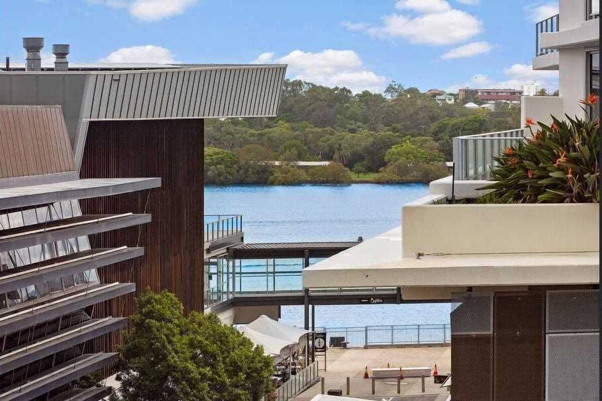 A modern building with a view of a lake and greenery.