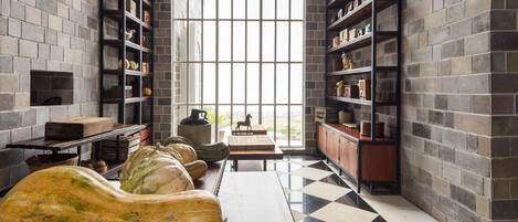 A spacious room with a large window, brick walls, and a checkered floor.