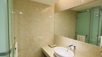 A modern bathroom with a glass shower enclosure, a beige marble countertop, and a large mirror.