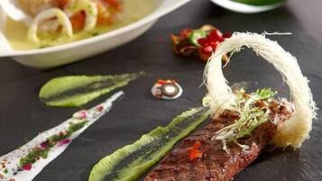 Un plato con bistecca, salsa verde y guarniciones sobre una pizarra.