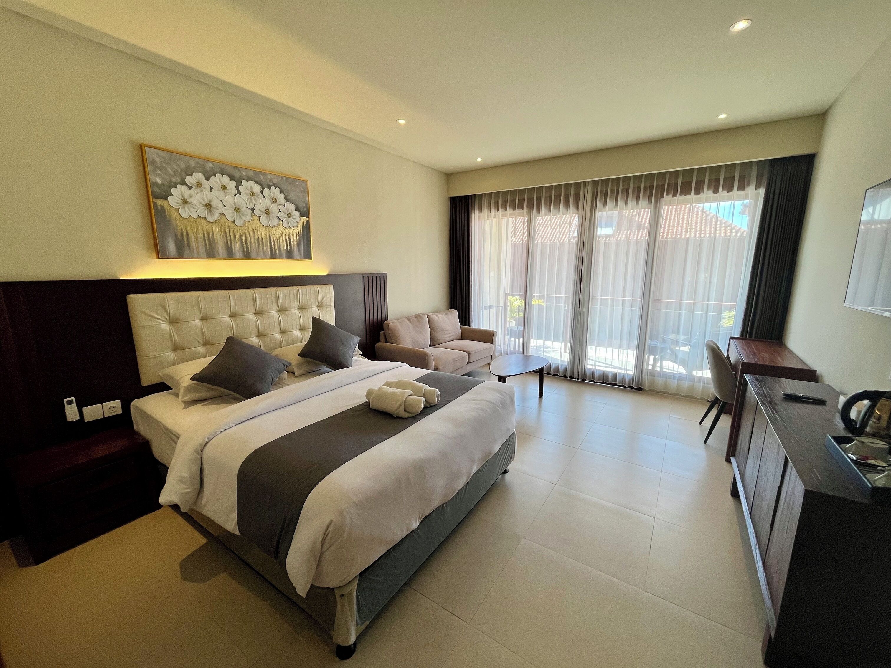 Habitación de hotel con una cama grande, un sofá, un escritorio y vistas al exterior a través de la ventana.