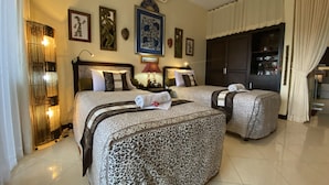 A hotel room with two beds, a large mirror, wall art, and a wardrobe. - Taman Agung Hotel (Denpasar)