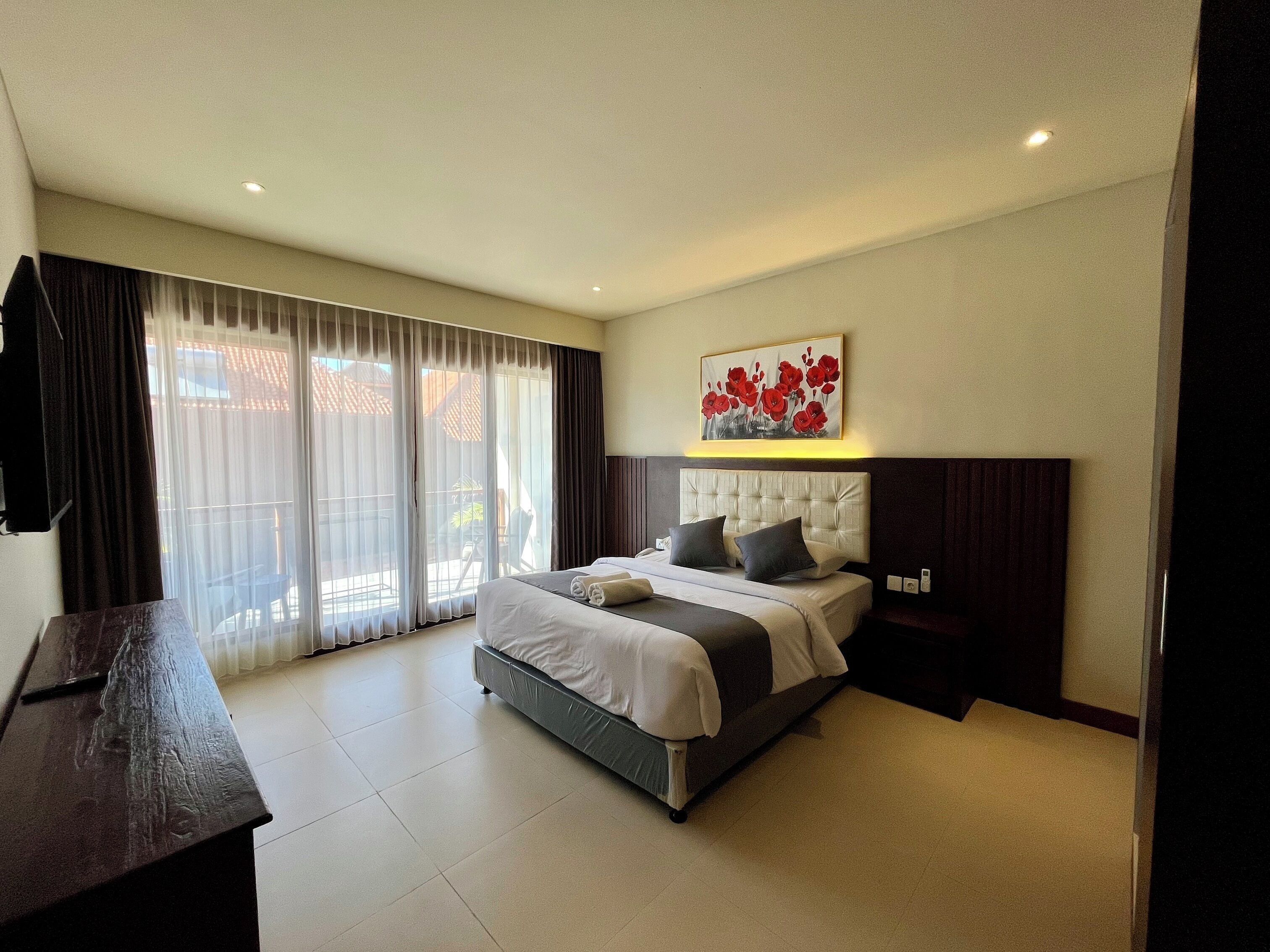 A modern hotel room with a large bed, a desk, and a view of the outdoors.