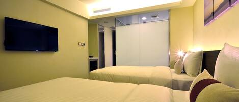 Habitación de hotel con dos camas, un televisor de pantalla plana montado en la pared y un espejo grande que refleja la habitación.