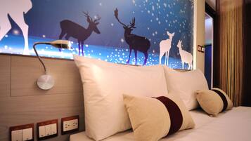 A hotel room with a bed, pillows, a wall-mounted lamp, and a wall decoration of deer silhouettes.