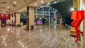 A spacious lobby with a high ceiling, a seating area with sofas and chairs, a large red sculpture, and a glass entrance leading to an outdoor area. - Freedom Design Hotel (Taoyuan City)