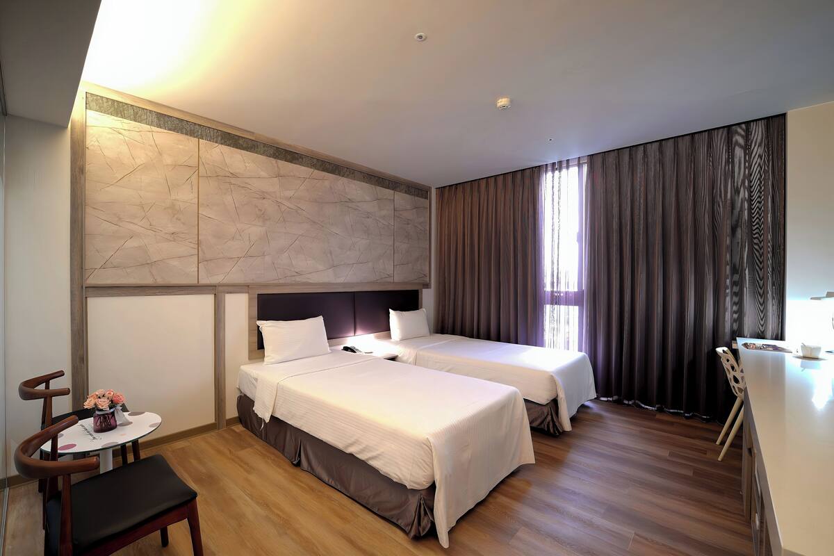 A hotel room with two beds, a desk, and a chair.