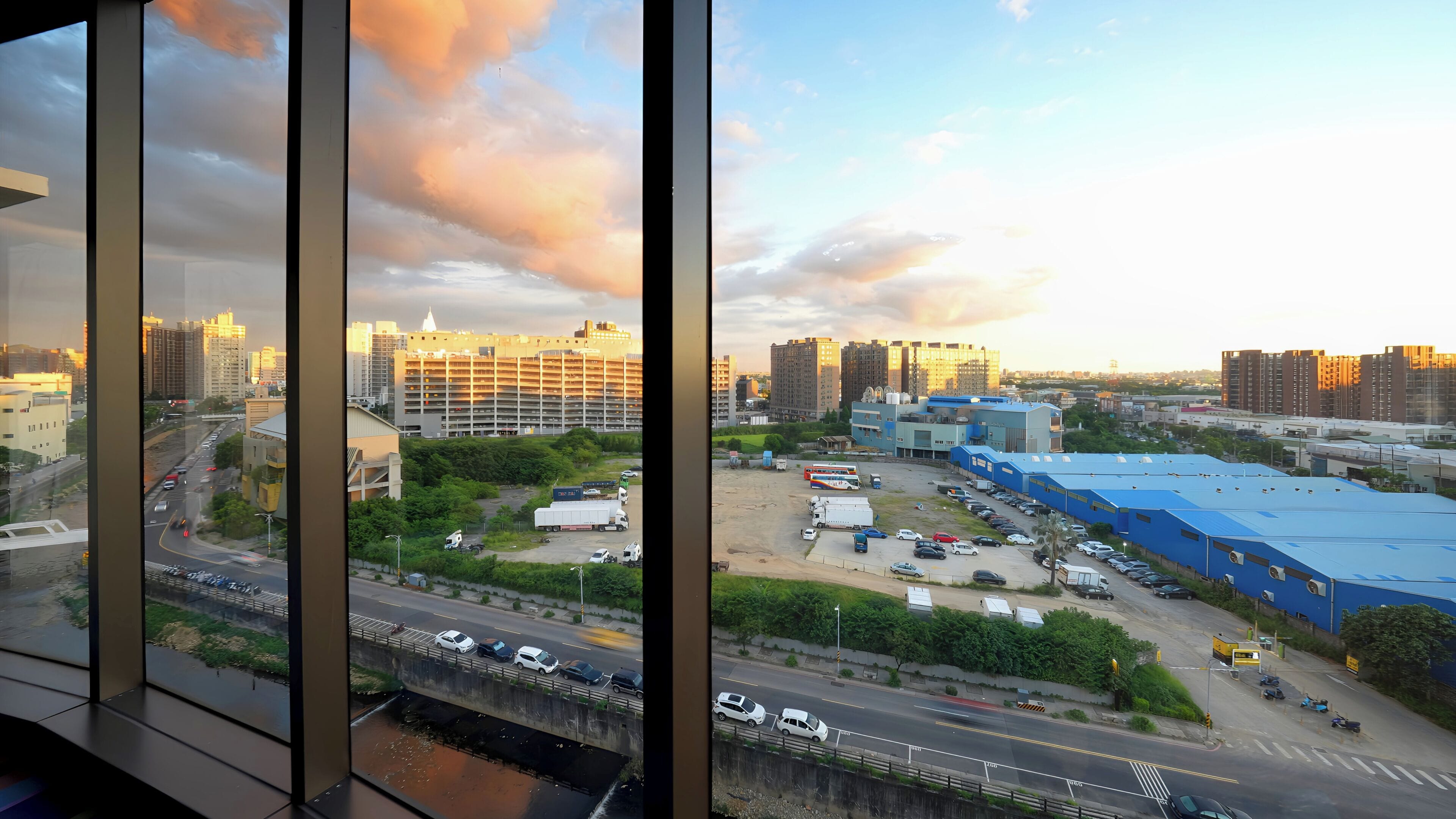 A cityscape with high-rise buildings, a parking lot, and a bridge.