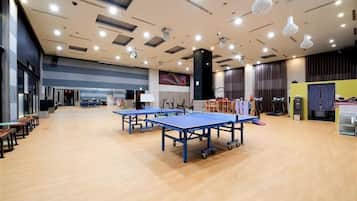 A spacious indoor area with ping pong tables, a large mural, and a stage with musical instruments.