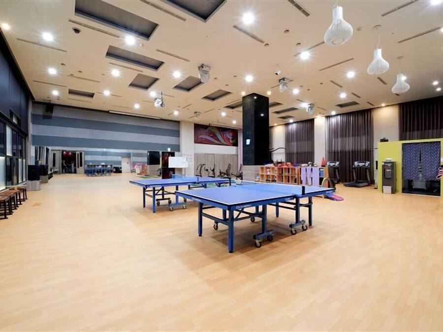 A spacious indoor area with ping pong tables, a large mural, and a stage with musical instruments.