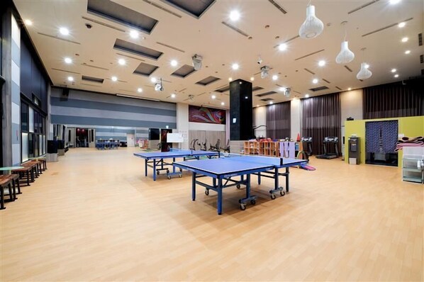 A spacious indoor area with ping pong tables, a large mural, and a stage with musical instruments. - Freedom Design Hotel (Taoyuan City)