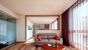A modern living room with a sofa, a coffee table, and a large window with curtains. - Freedom Design Hotel (Taoyuan City)
