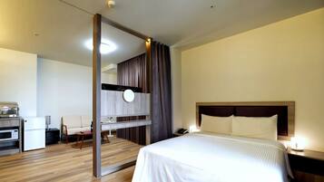 Habitación de hotel moderna con una cama grande, mesita de noche y un escritorio integrado con computadora e impresora.