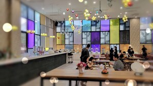 A modern restaurant with a long counter, multiple dining tables, and a variety of hanging lights. - Freedom Design Hotel (Taoyuan City)