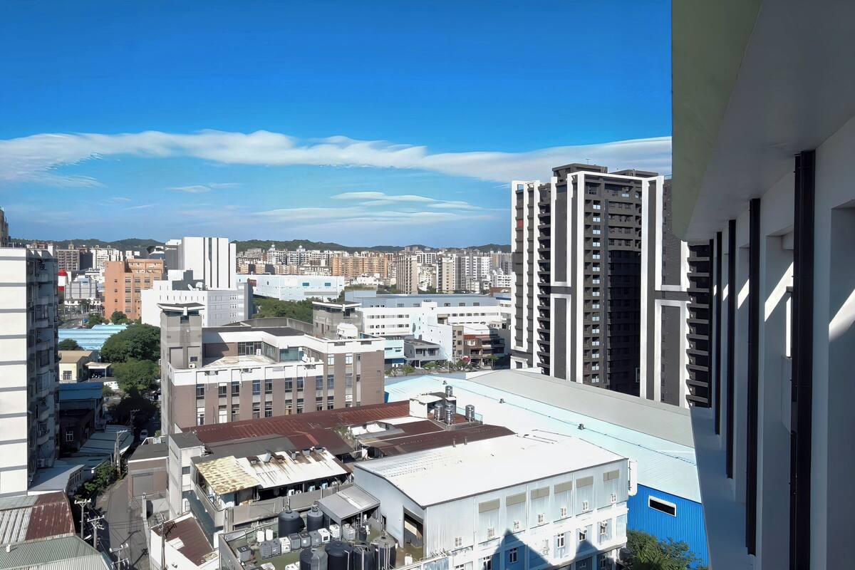 A high-rise building with multiple floors, a mix of residential and commercial buildings, and a clear blue sky.