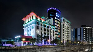 A modern hotel with multiple floors, illuminated signage, and a prominent cylindrical tower. - Freedom Design Hotel (Taoyuan City)