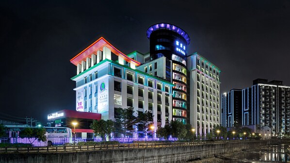 A modern hotel with multiple floors, illuminated signage, and a prominent cylindrical tower.