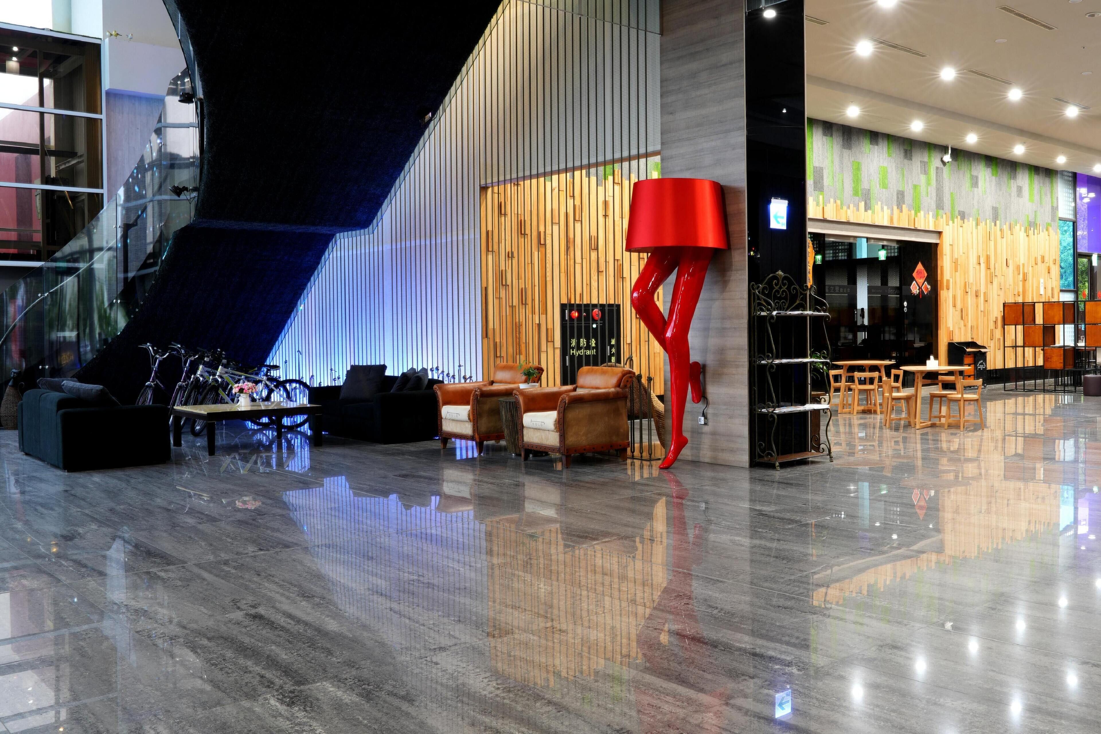 A modern lobby with a staircase, seating area, and a red lamp.