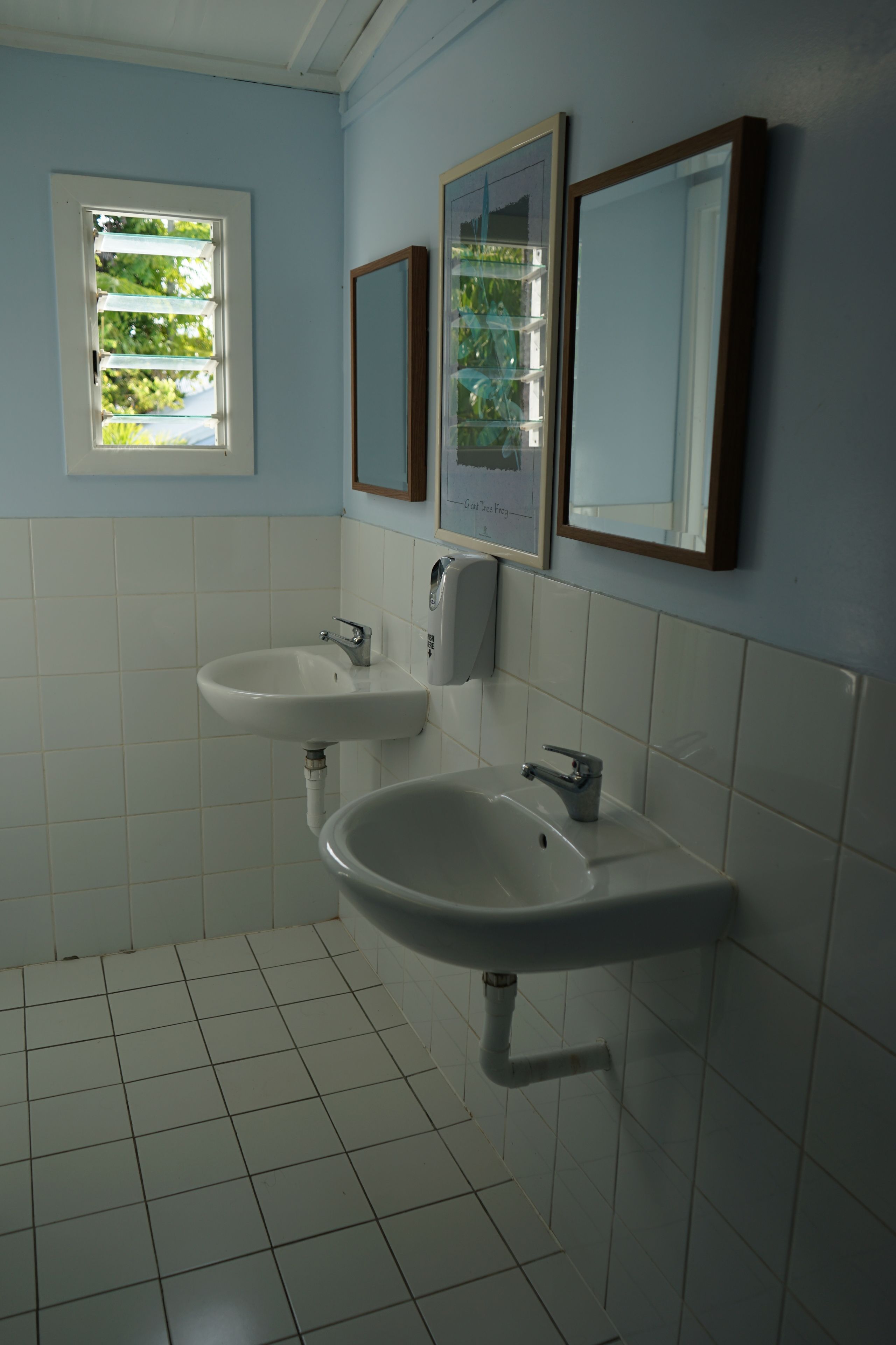 A bathroom with two sinks, a window, and three mirrors.