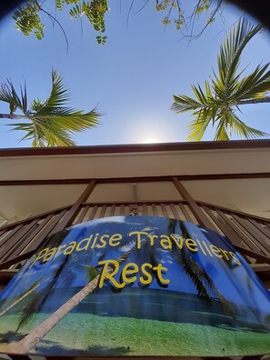 A sign for Paradise Travellers Rest with palm trees and a clear sky in the background. - Travellers Paradise Heritage Historical Place - Hostel (Parramatta Park)