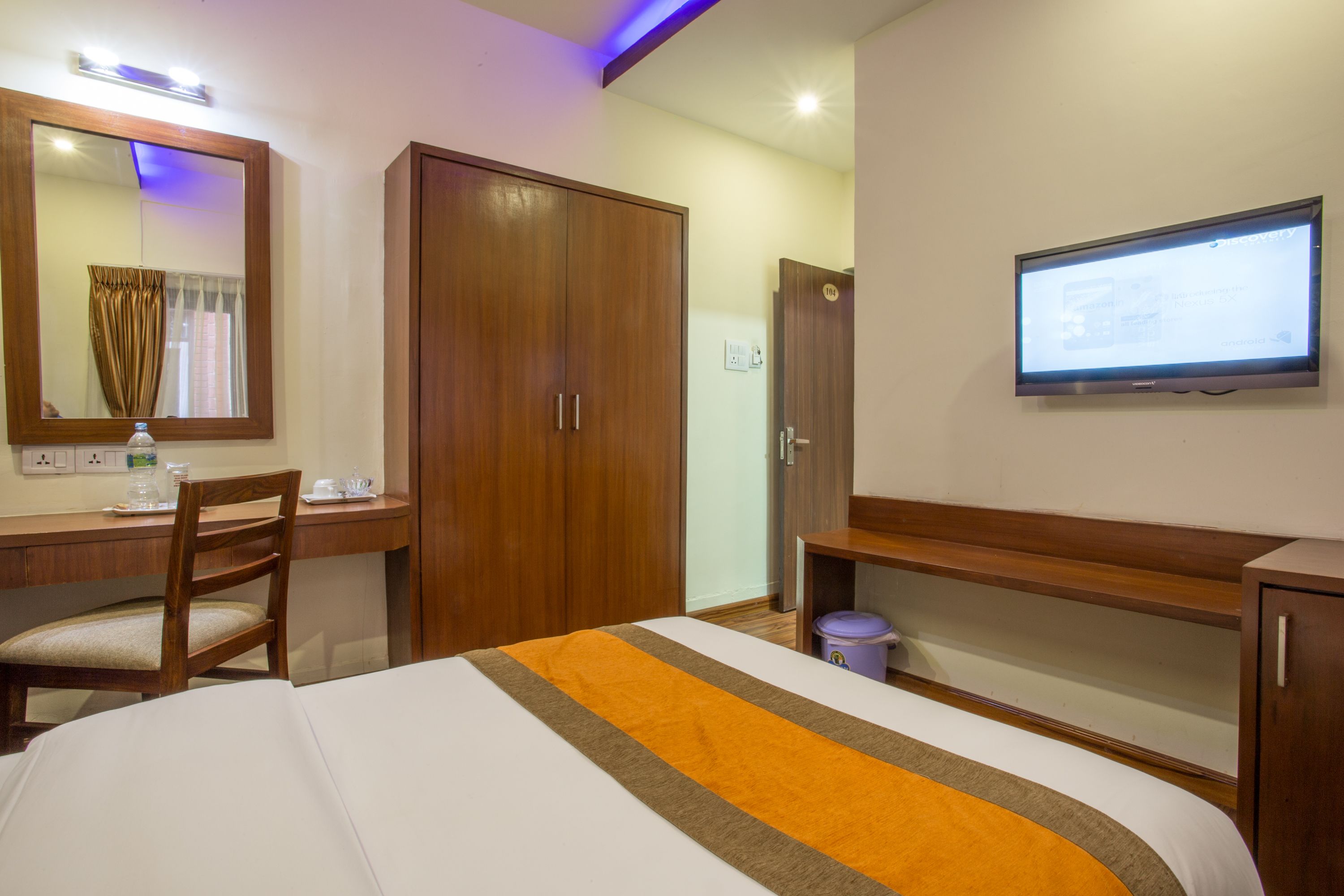 Una habitación de hotel con cama, escritorio, silla, televisión y armario.