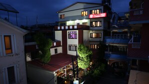 A multi-story hotel with a red and white facade, multiple balconies, and a visible restaurant area. - Aryatara Kathmandu Hotel (Kathmandu)