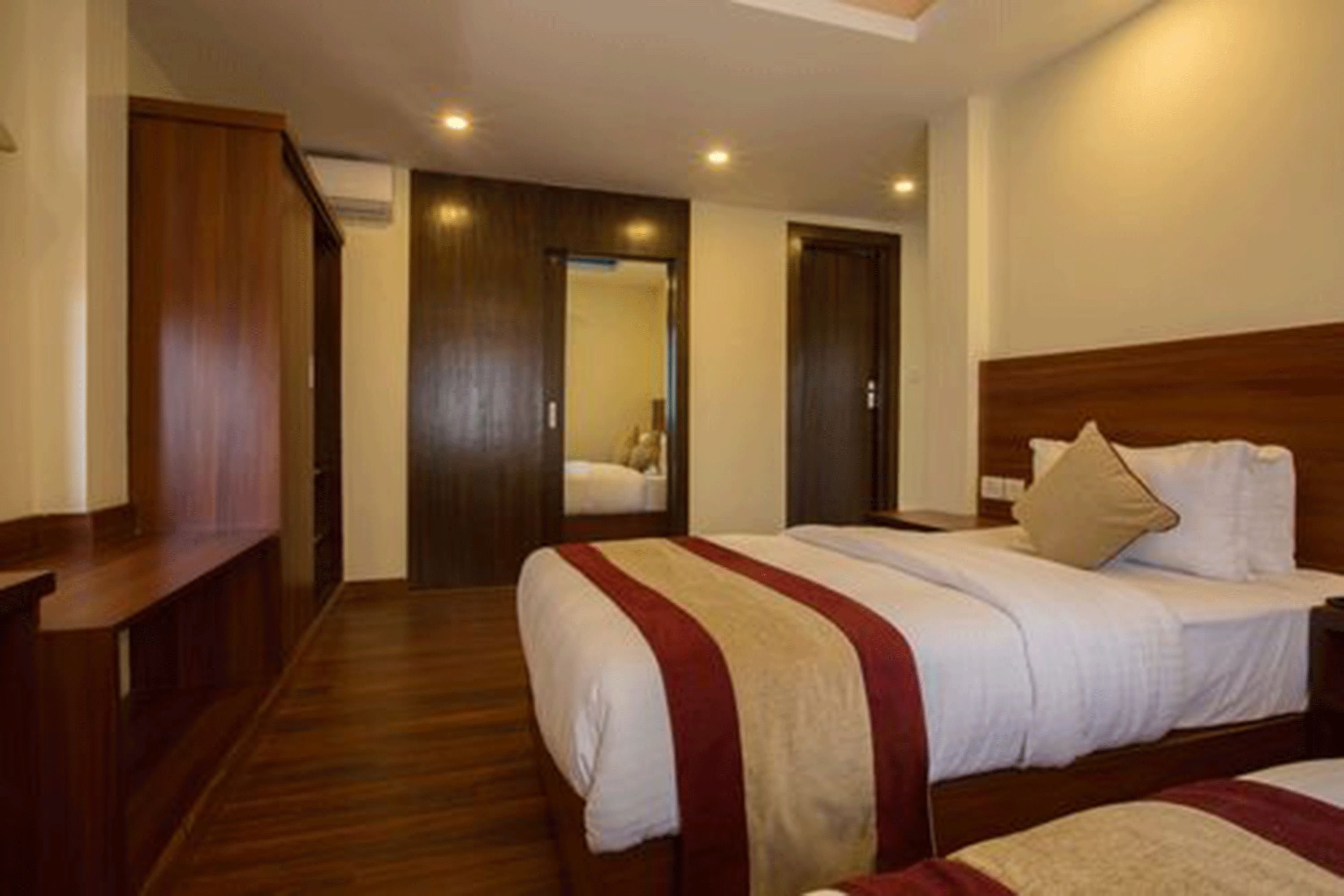 A hotel room with two beds, wooden flooring, and a wooden headboard.