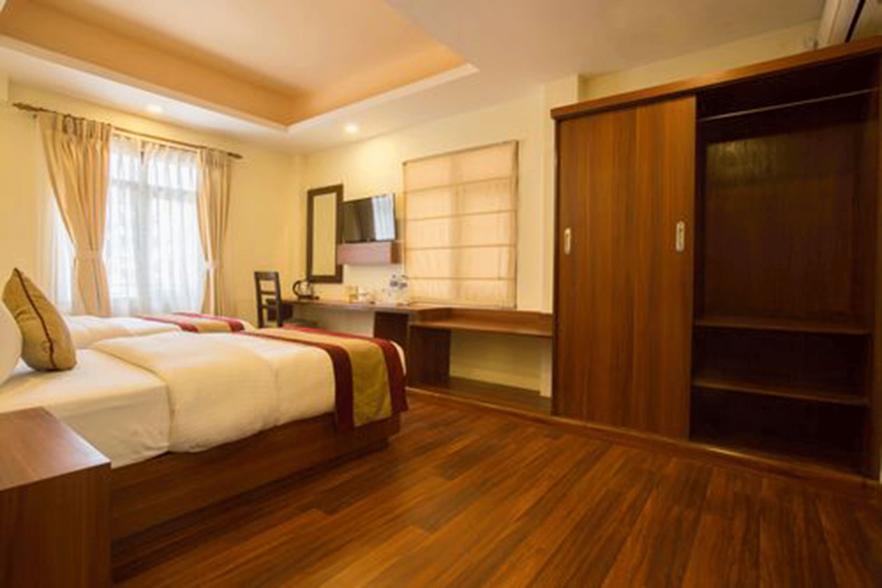Una habitación de hotel con cama, suelo de madera, escritorio, espejo y armario.