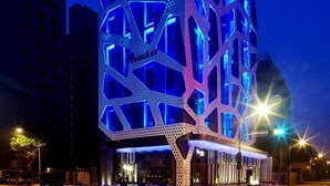 Moderni hotelli, jossa on ainutlaatuinen, geometrisesti muotoiltu julkisivu ja valaistut kyltit.