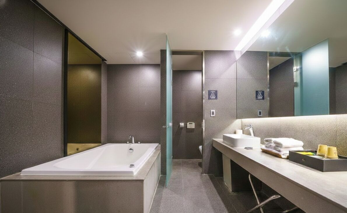 A modern bathroom with a large bathtub, a sink, and a mirror. There are towels and toiletries on the counter.
