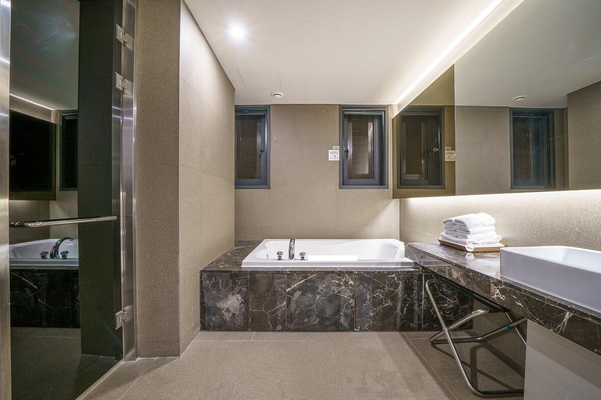 Un baño moderno con una bañera de mármol, un lavabo independiente y una cabina de ducha de vidrio.