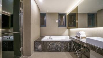 Un baño moderno con una bañera de mármol, un lavabo independiente y una cabina de ducha de vidrio.
