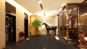 Eine Lobby mit schwarzem Fliesenboden, einer Pferdestatue, einem Topfpflanzen und einer Lampe.
