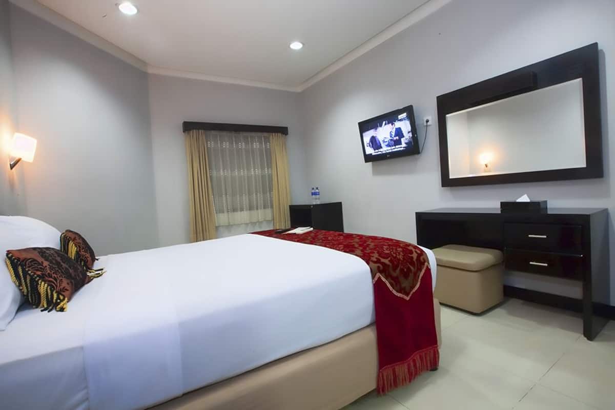 A hotel room with a bed, a TV, a desk, and a chair.