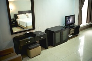 A hotel room with a bed, a TV, a desk, a cabinet, and a mirror. - Hotel Celebes (Makassar)